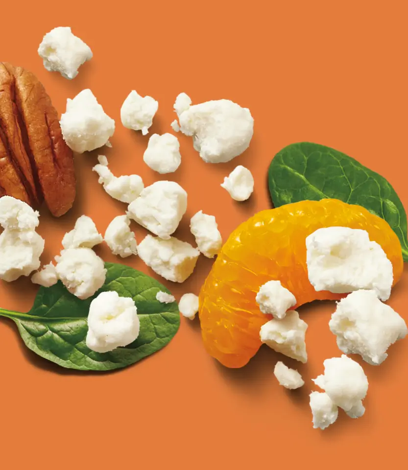Popcorn, bacon strips, orange citrus slice, and fresh spinach leaves arranged on an orange background.